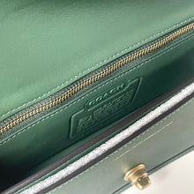 Load image into Gallery viewer, Close-up of a green Coach handbag with gold zipper and logo.