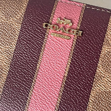 Load image into Gallery viewer, Close-up of a Coach wallet with a gold logo on a striped pattern.