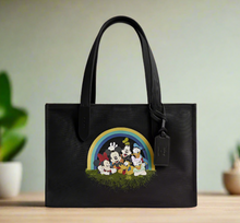 Load image into Gallery viewer, Black tote bag with cartoon characters and rainbow design on a wooden surface.