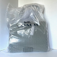 Load image into Gallery viewer, Coach tote bag wrapped in clear plastic on a white background