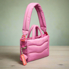 Load image into Gallery viewer, Pink quilted handbag with orange tag on a light gray background