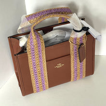 Load image into Gallery viewer, Brown Coach handbag with a straw handle featuring purple and gold accents on a white background.
