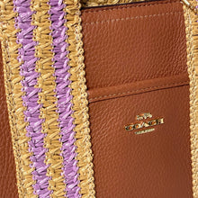 Load image into Gallery viewer, Close-up of a brown leather wallet with purple and gold woven strap, featuring the Coach logo.