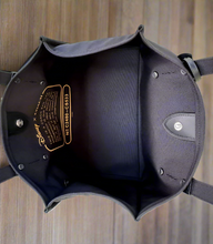 Load image into Gallery viewer, Black leather bag with disney branding on a wooden surface