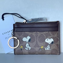 Load image into Gallery viewer, Coach x Peanuts keychain pouch with Snoopy and Woodstock design on a light blue background
