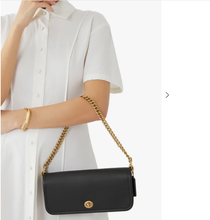 Load image into Gallery viewer, Black handbag with gold chain strap held by a person wearing a white shirt.