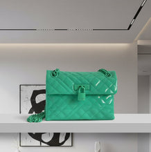 Load image into Gallery viewer, Green quilted handbag on a white shelf in a modern interior setting