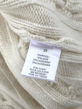Load image into Gallery viewer, Close-up of a label on a textured beige fabric with text.