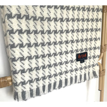 Load image into Gallery viewer, Houndstooth patterned blanket with a brand label on a white background