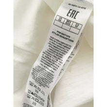 Load image into Gallery viewer, Clothing label with text and symbols on a white fabric background