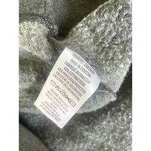 Load image into Gallery viewer, Close-up of a fabric label on a textured gray fabric background