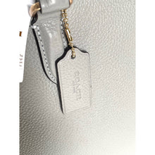 Load image into Gallery viewer, Close-up of a silver handbag with a visible brand tag on a white background