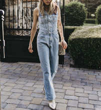 Load image into Gallery viewer, Woman wearing denim overalls walking on a paved path with greenery in the background