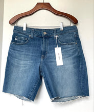 Load image into Gallery viewer, Blue denim shorts on a hanger with a tag against a white background