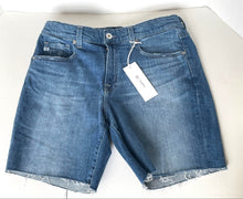 Load image into Gallery viewer, Folded blue denim jeans with a tag on a white background