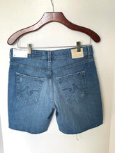 Load image into Gallery viewer, Blue denim shorts on a hanger against a white background