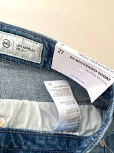 Load image into Gallery viewer, Close-up of AG jeans with label and tag on a beige background