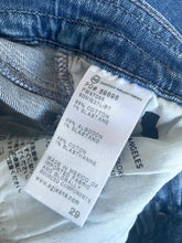 Load image into Gallery viewer, Close-up of a denim garment's inner label showing text including '99% COTON 1% ELASTANE', 'MADE IN MEXICO', and the website 'www.agjmans.