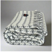 Load image into Gallery viewer, Folded gray and white patterned blanket with a brand tag on a gray background
