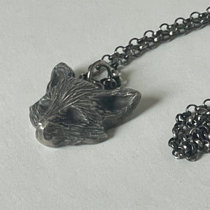 Silver fox pendant on a chain against a light gray background