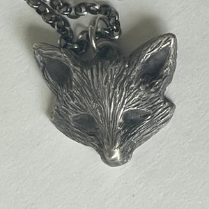 Silver leaf-shaped pendant on a chain against a light background