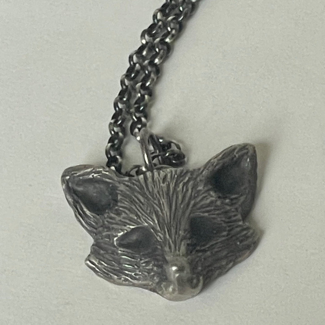Silver fox pendant on a chain against a light gray background