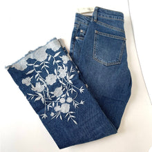 Load image into Gallery viewer, Folded blue jeans with floral embroidery on a white background