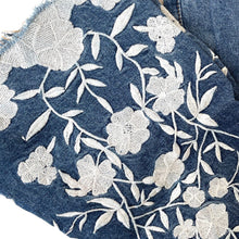 Load image into Gallery viewer, Close-up of denim fabric with white floral embroidery