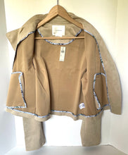 Load image into Gallery viewer, A tan suede-like jacket with contrasting blue and white floral patterned trim, hanging on a wooden hanger against a white background.