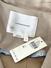 Load image into Gallery viewer, Close-up of a beige garment interior showing a white Anthropologie brand label and a size/tag card.
