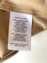 Load image into Gallery viewer, A close-up of a beige garment's interior label showing product details in English, French, and Spanish, including material composition and origin.