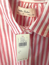 Load image into Gallery viewer, A close-up of a red and white vertically striped button-down shirt by Isabelle Sinclair, featuring a cream-colored brand label and a white product tag with a barcode.