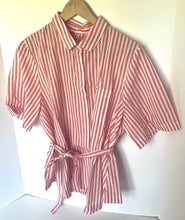 Load image into Gallery viewer, A short-sleeve collared shirt dress with vertical pink and white stripes, featuring a tie belt at the waist, hanging on a wooden hanger against a plain white wall.