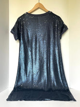 Load image into Gallery viewer, A short-sleeve black sequined t-shirt dress hanging on a wooden hanger against a plain off-white wall.