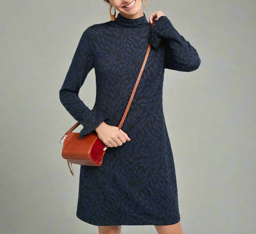 Woman wearing a blue patterned dress holding a brown handbag with a red interior.