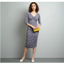 Load image into Gallery viewer, Woman wearing a patterned dress holding a yellow clutch against a gray background