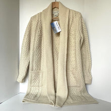 Load image into Gallery viewer, Beige cable knit cardigan on a hanger with a visible brand tag against a white background