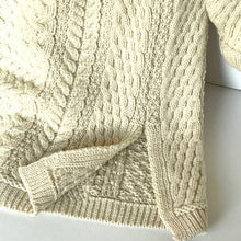 Load image into Gallery viewer, Close-up of a cream-colored cable knit sweater on a white background