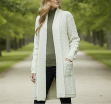 Load image into Gallery viewer, Woman wearing a long cream cardigan with a blurred green foliage background