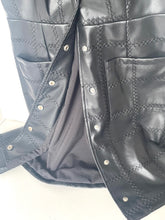 Load image into Gallery viewer, Close-up of a black quilted faux-leather vest with diamond stitching, silver snap buttons, and side pockets.