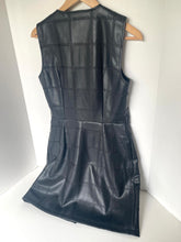 Load image into Gallery viewer, A sleeveless black faux-leather dress with a quilted grid pattern, hanging on a wooden hanger against a white background.