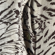 Load image into Gallery viewer, Close-up of fabric with black abstract pattern and a button on a beige background