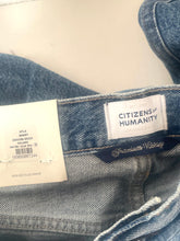 Load image into Gallery viewer, Close-up of the inside waistband of a pair of blue denim jeans, showing the Citizens of Humanity brand label, a dark navy Premium Chicago label, and a white size tag.