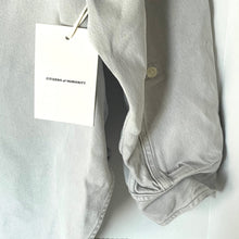Load image into Gallery viewer, Light gray shirt with a 'Citizens of Humanity' tag on a white background