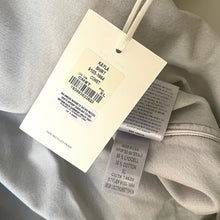 Load image into Gallery viewer, Clothing tag on a gray fabric background
