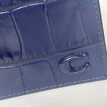Load image into Gallery viewer, Close-up of a blue textured wallet with a brand logo on a light background