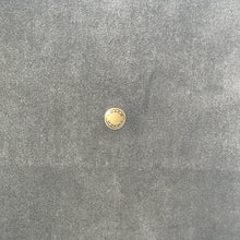 Load image into Gallery viewer, Gold button on a textured gray fabric background