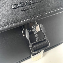 Load image into Gallery viewer, Close-up of a Coach bag with a buckle detail on a light gray background