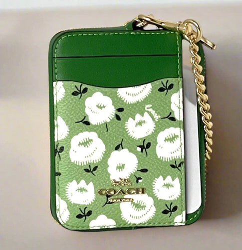 Green Coach wallet with floral pattern and gold chain on a white background