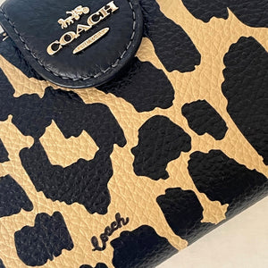 Close-up of a Coach wallet with leopard print pattern and visible brand logo.